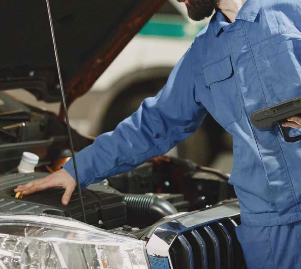 A technician inspecting a used vehicle at Automotive Solutions